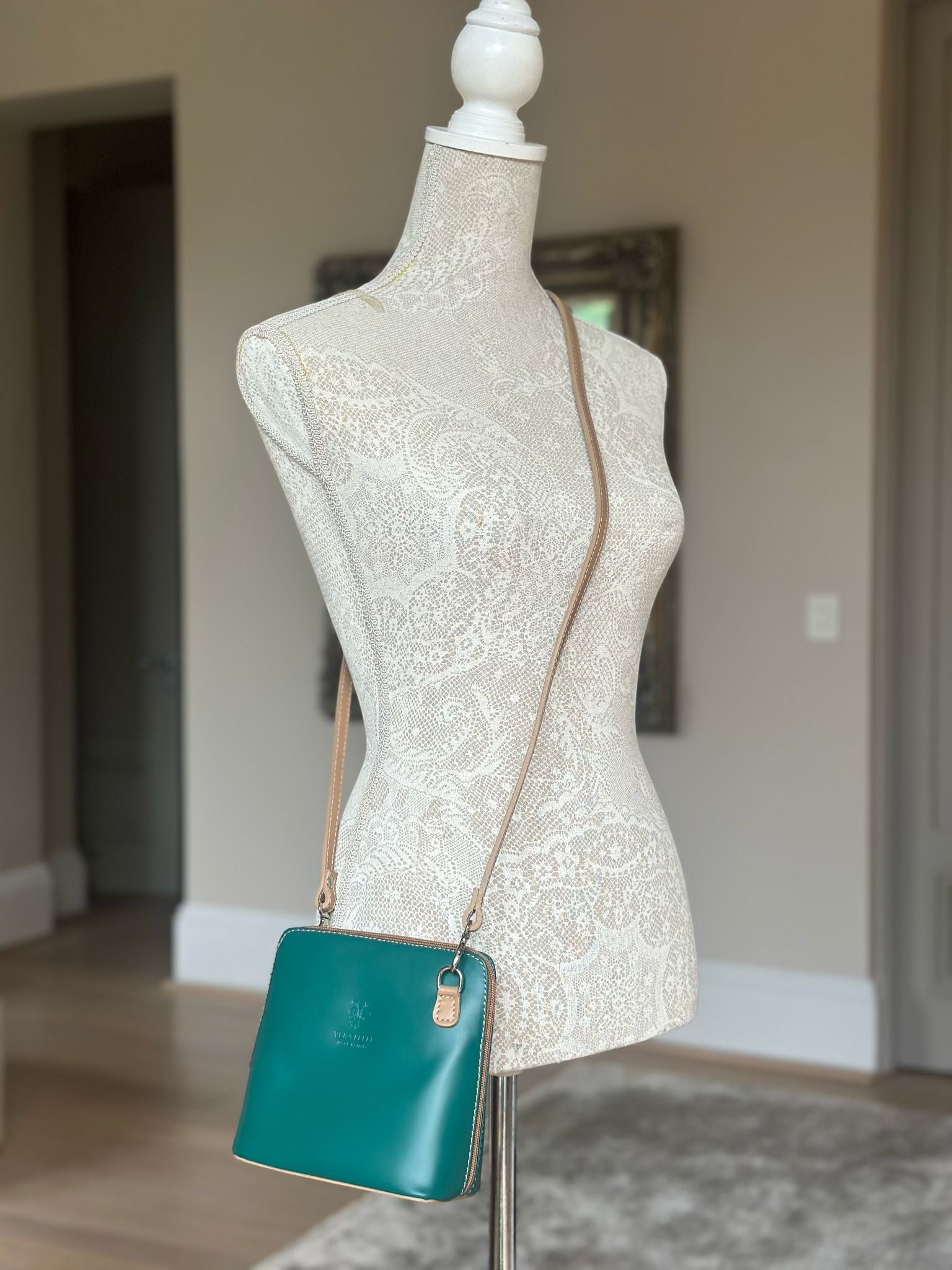 Eclectic Mini Milano green smooth leather crossbody bag with silver hardware on a lace-covered mannequin