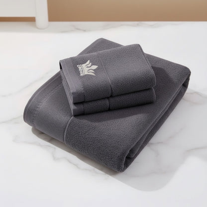 Eclectic grey cotton guest towel featuring an elegant embroidered crown detail on a white marble surface.