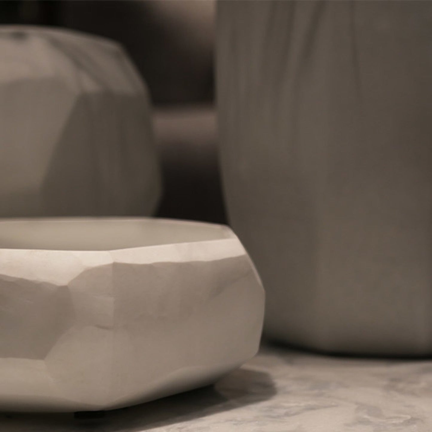 Eclectic Guaxs Cubistic opal white glass vase with faceted hand-cut surface and matte finish on a stone surface