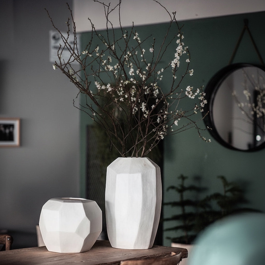 Eclectic Guaxs Cubistic opal white glass vases with faceted surfaces displayed on a wooden table with flowering branches