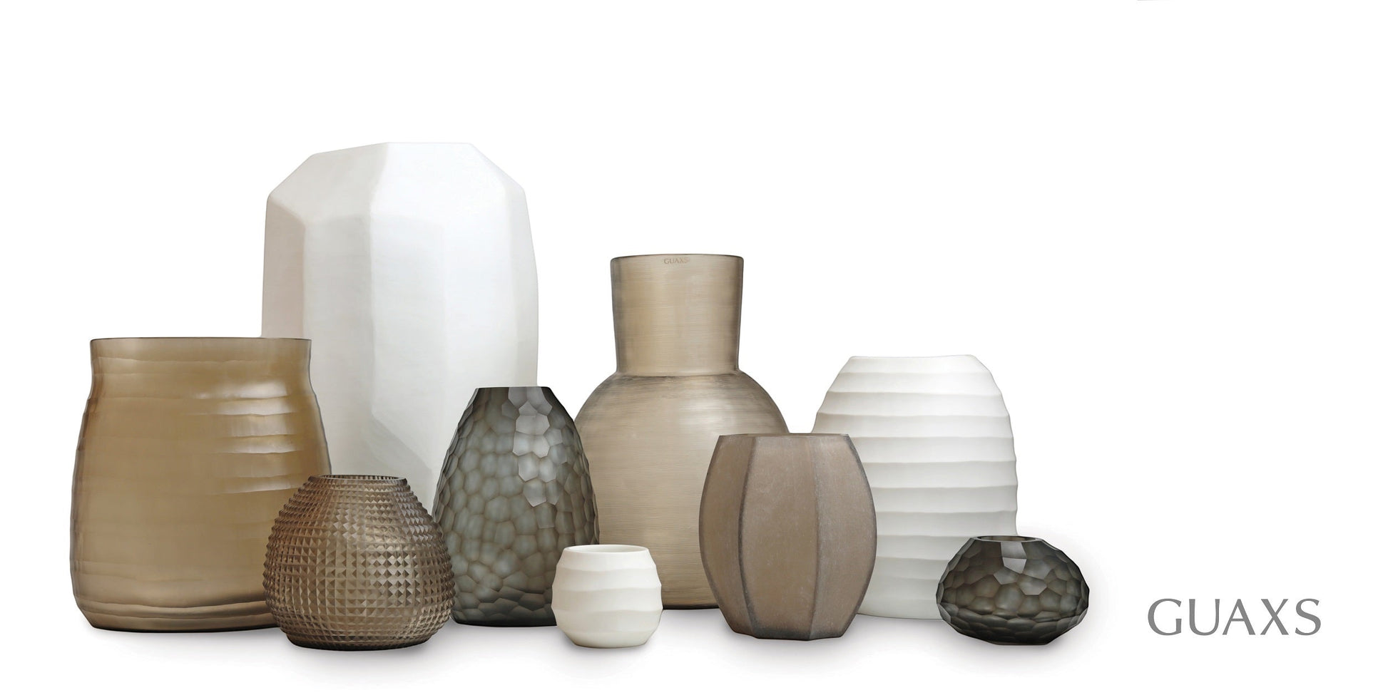 Eclectic collection of Guaxs mouth-blown glass vases in various shapes, sizes, and neutral opal and grey tones.