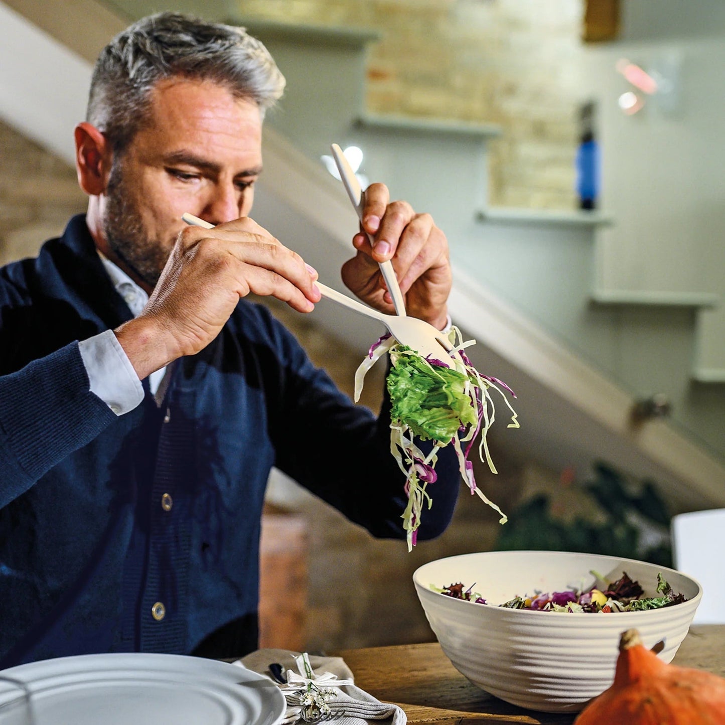 Eclectic Guzzini Tierra milk white recycled plastic salad servers being used by a man to toss a fresh salad