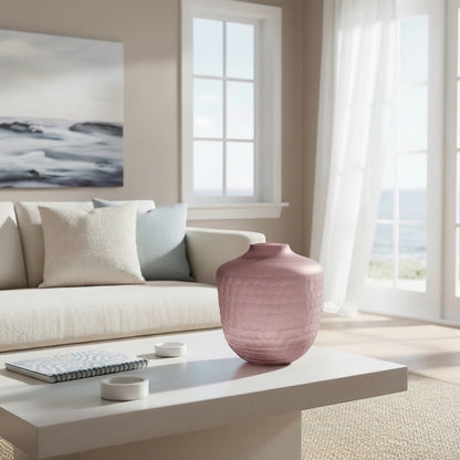 Eclectic hammered mauve glass vase on a white coffee table in a modern living room with a neutral sofa.