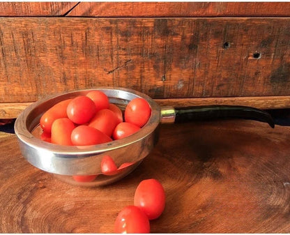 Eclectic Impondo Zulu pewter dish with a resin antelope horn handle, filled with cherry tomatoes on a wooden surface.