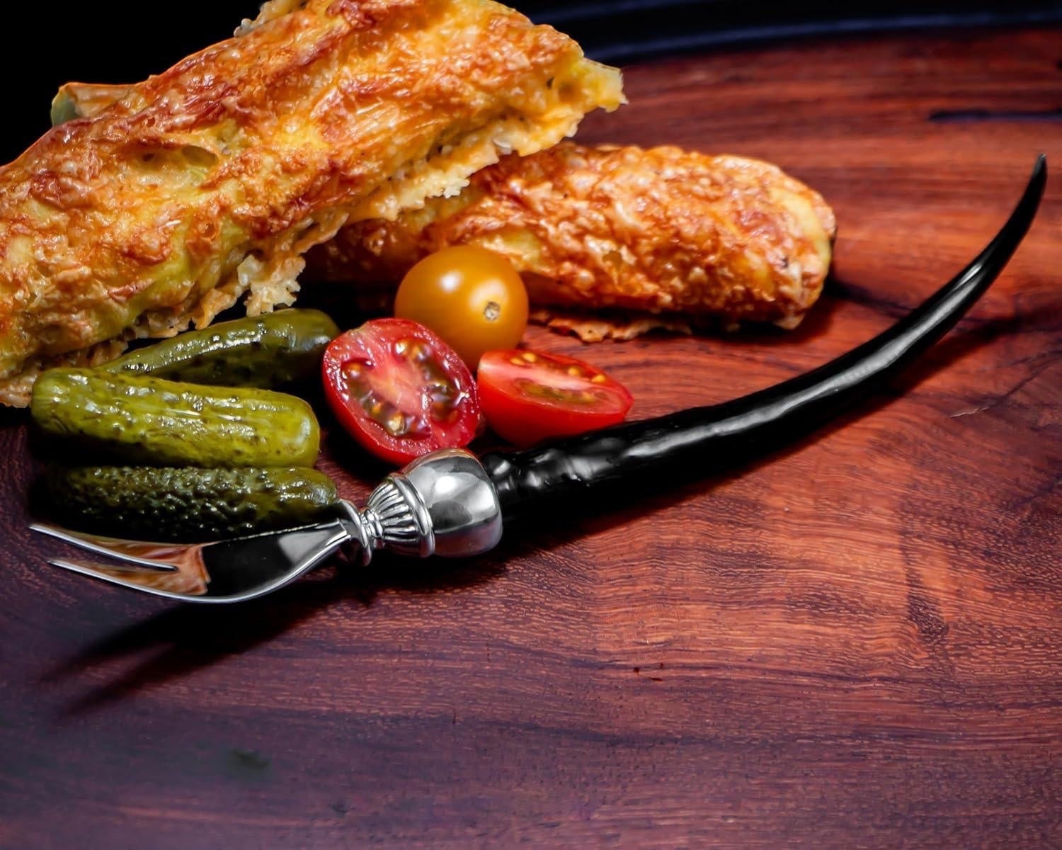 Eclectic Impondo Zulu pickle fork with a black resin horn-style handle and pewter detail on a wooden serving board.