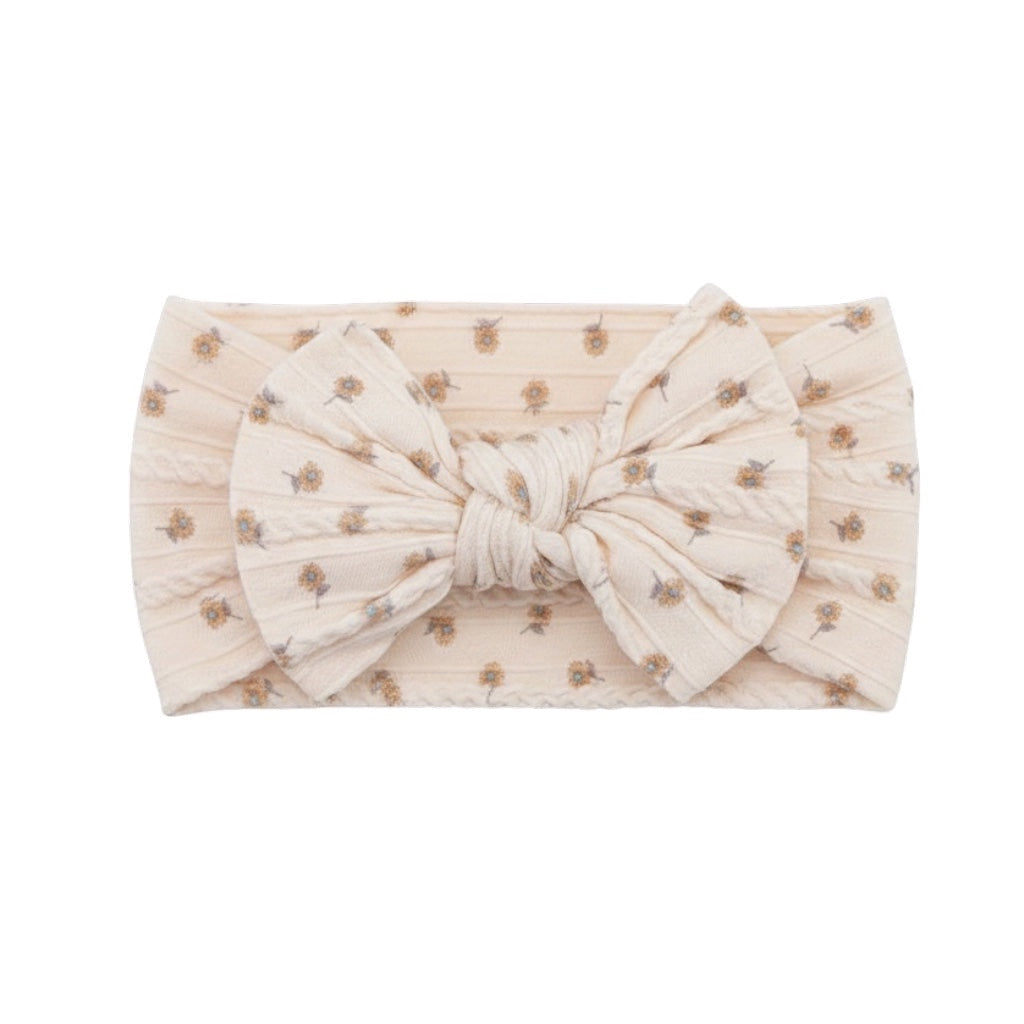 Eclectic ivory baby headband featuring a delicate floral print and a soft, stretchy fabric bow design.