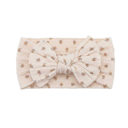 Eclectic ivory baby headband featuring a delicate floral print and a soft, stretchy fabric bow design.