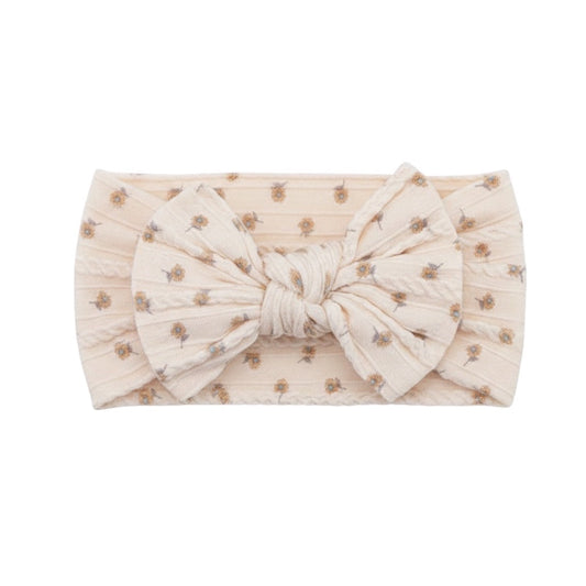 Eclectic ivory baby headband featuring a delicate floral print and a soft, stretchy fabric bow design.