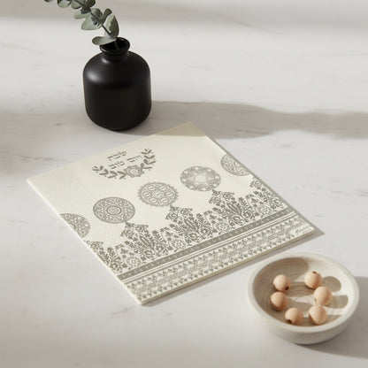 Eclectic Jewish Heritage silver and white airlaid disposable napkin with ornamental motifs on a marble table.