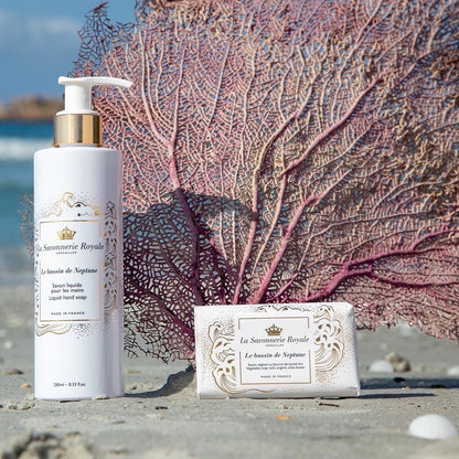 Eclectic La Savonnerie Royale Le Bassin de Neptune liquid soap and bar soap set on a sandy beach with coral decor.