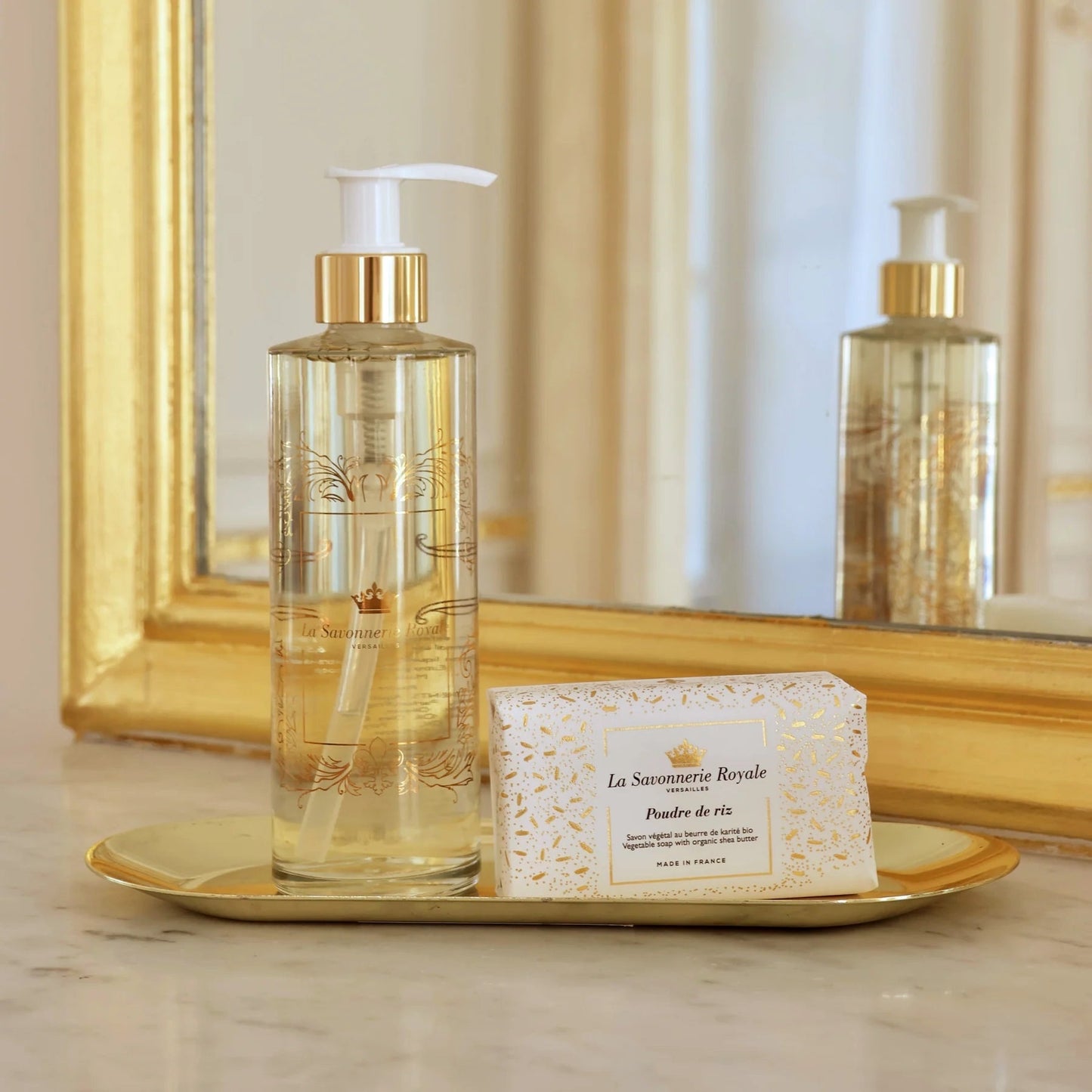 Eclectic La Savonnerie Royale Poudre de Riz soap bar and liquid soap dispenser on a gold tray in front of a mirror.