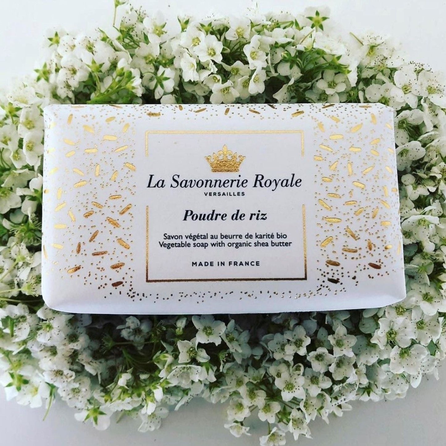 Eclectic La Savonnerie Royale Poudre de Riz soap bar in decorative white and gold packaging nestled in white flowers.