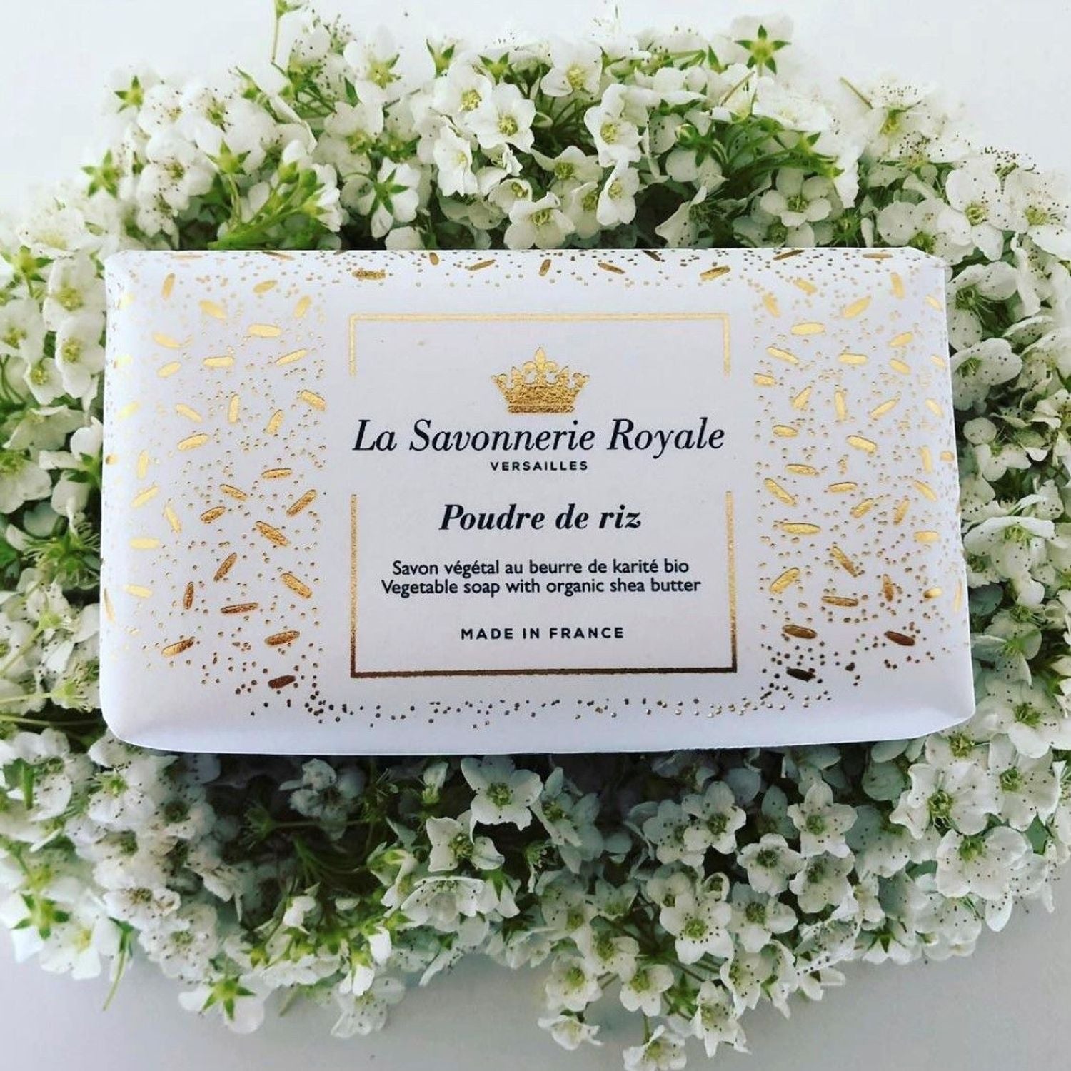 Eclectic La Savonnerie Royale Poudre de Riz soap bar in decorative white and gold packaging nestled in white flowers.
