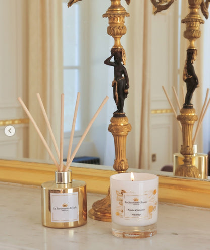 Eclectic La Savonnerie Royale Petales d’Eglantine candle and reed diffuser on a marble surface with gold accents.