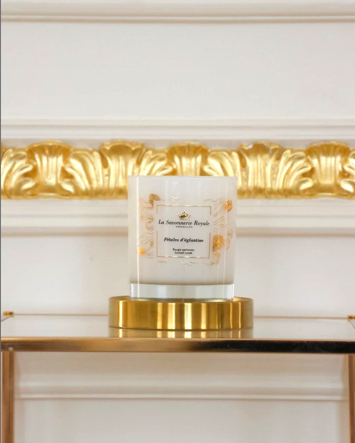 Eclectic La Savonnerie Royale Petales d’Eglantine candle in an ornate glass vessel with gold accents on a gold base.