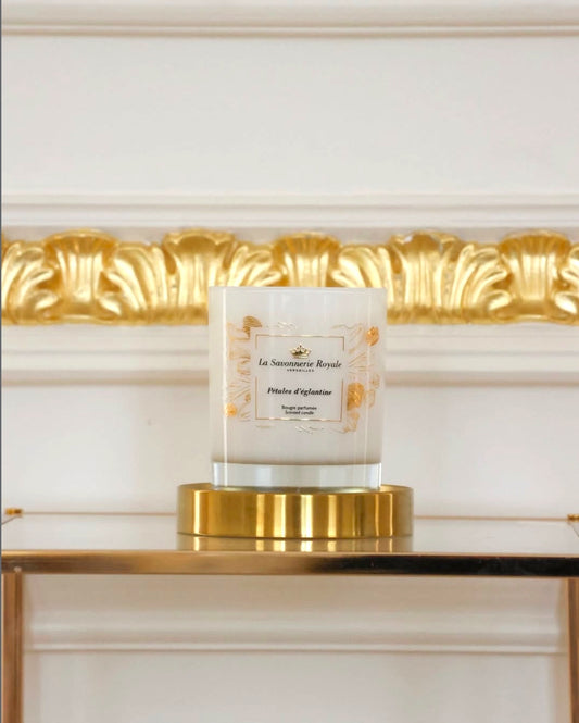 Eclectic La Savonnerie Royale Petales d’Eglantine candle in an ornate glass vessel with gold accents on a gold base.