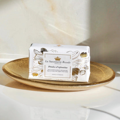 Eclectic La Savonnerie Royale Petales d'Eglantine rose soap in illustrated paper wrap on a gold decorative dish.
