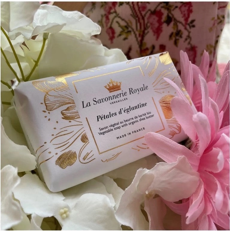 Eclectic La Savonnerie Royale Petales d'Eglantine soap bar in decorative white and gold packaging among floral petals