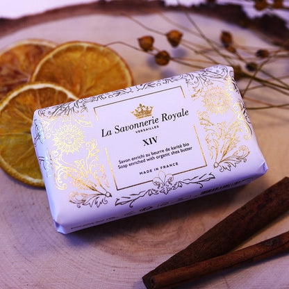 Eclectic La Savonnerie Royale XIV soap bar in ornate white and gold packaging with dried orange slices and cinnamon.