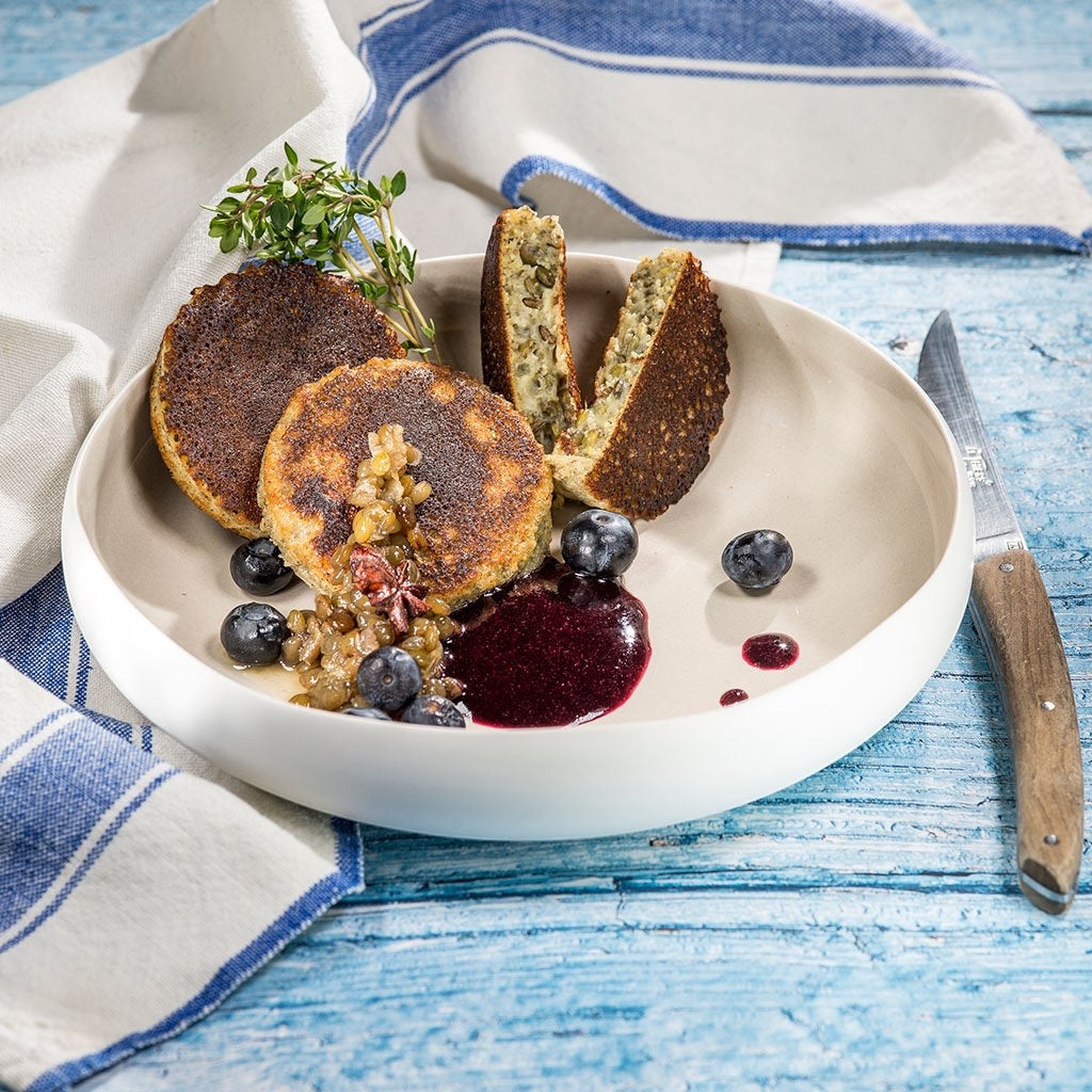 Eclectic Médard de Noblat Oslo stoneware serving bowl with a linen interior, holding savory pancakes and blueberries.