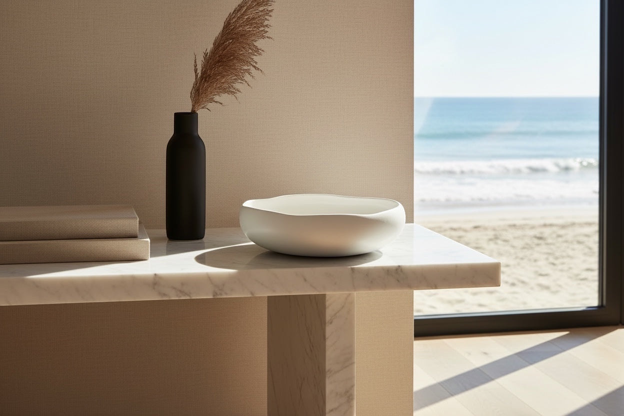 Eclectic Médard de Noblat Oslo white stoneware serving bowl with organic shape on a marble table by the beach.