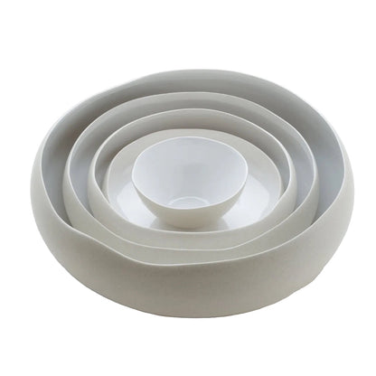 Eclectic Médard de Noblat Oslo white stoneware serving bowls nested together with matte linen and glossy finishes.