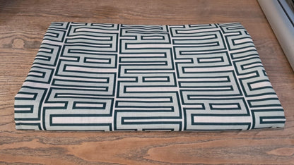 Eclectic mint green geometric tablecloth with a linen-look finish folded on a wooden table.