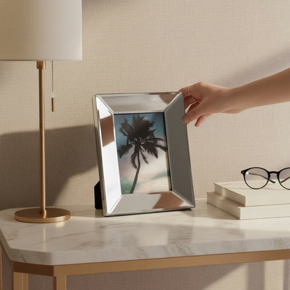 Eclectic mirrored bevelled photo frame on a marble console table with a hand adjusting the frame