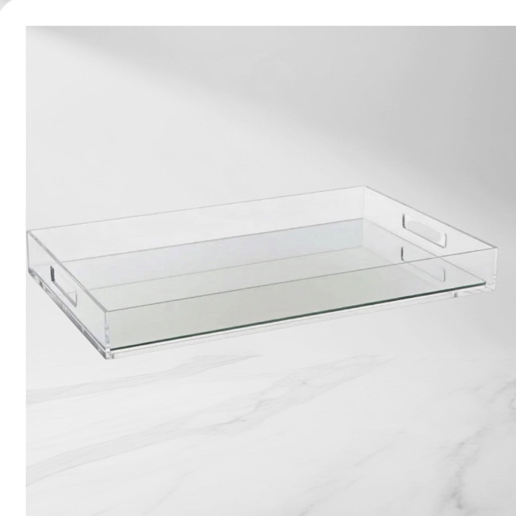 Eclectic mirrored clear acrylic serving tray with integrated handles on a white marble surface.