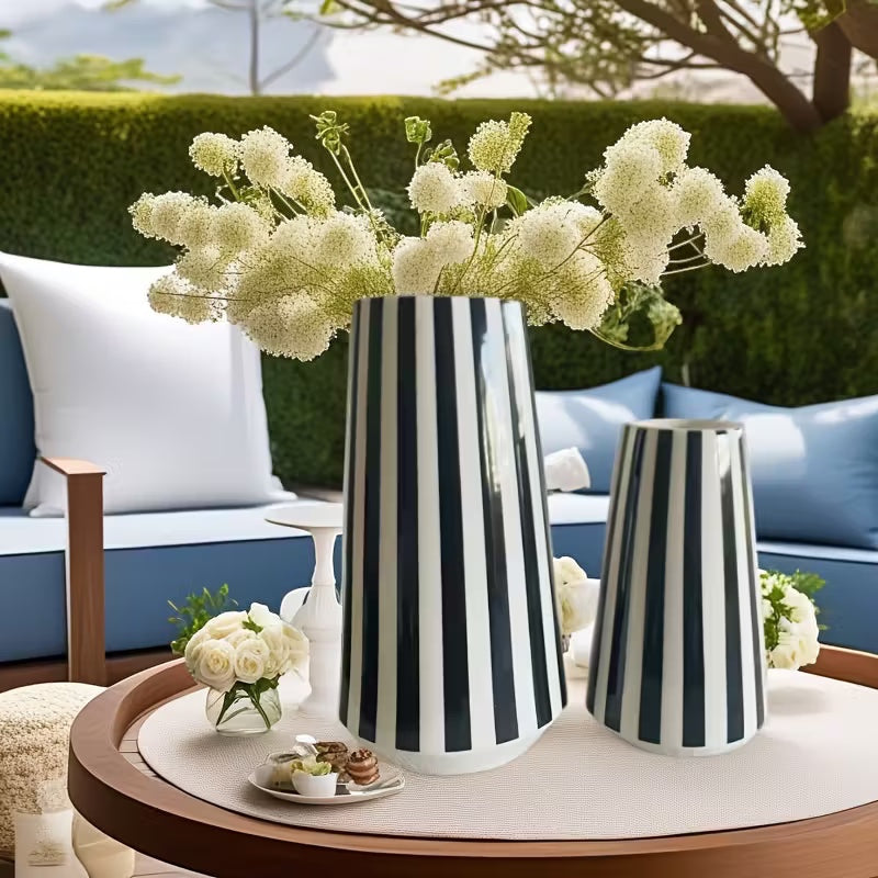Eclectic set of two monochrome ceramic vases with black and white vertical stripes on a round outdoor patio table.