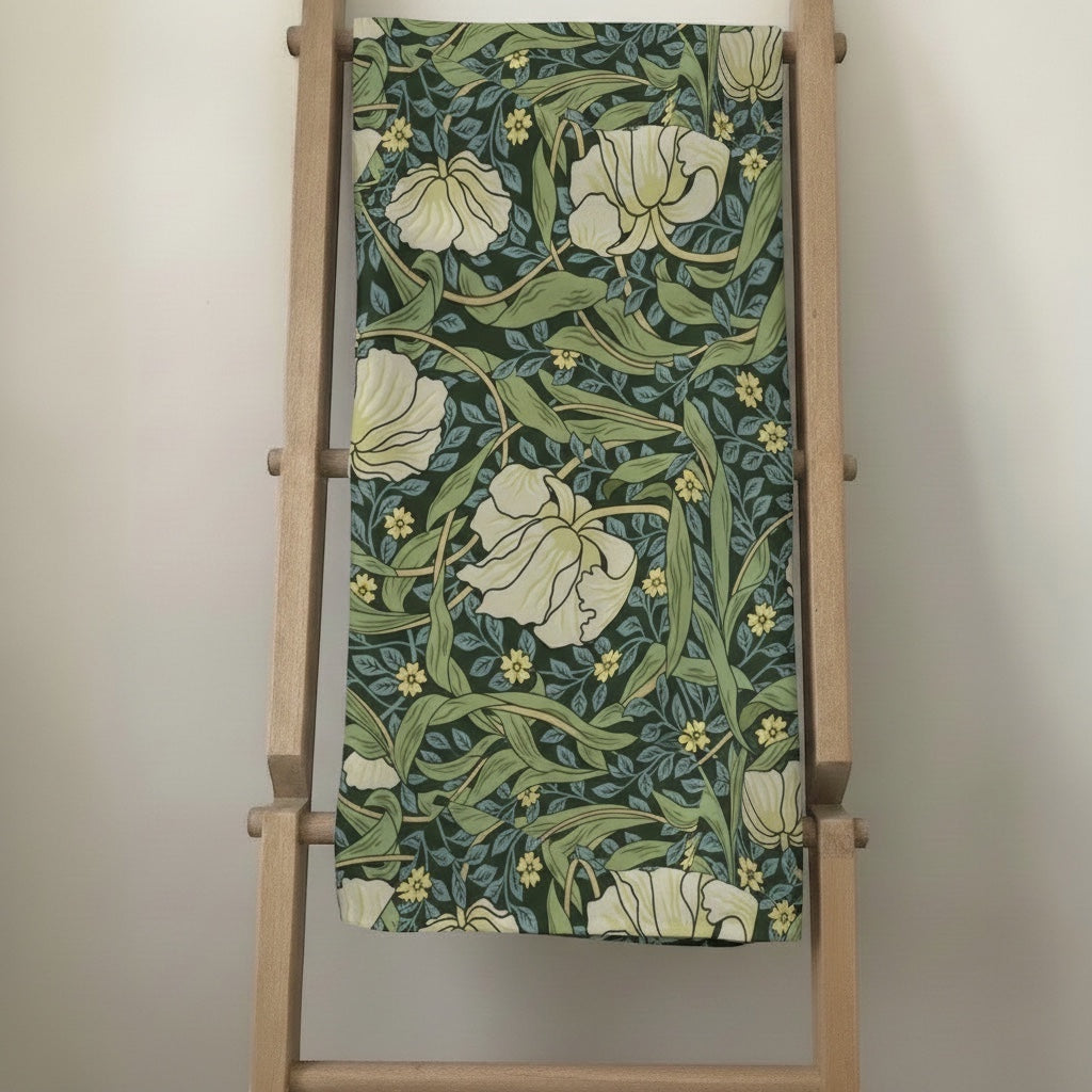 Eclectic Morris vintage floral tablecloth in green, cream, and yellow linen-blend fabric draped over a wooden ladder.
