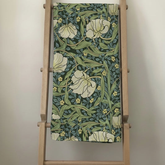 Eclectic Morris vintage floral tablecloth in green, cream, and yellow linen-blend fabric draped over a wooden ladder.