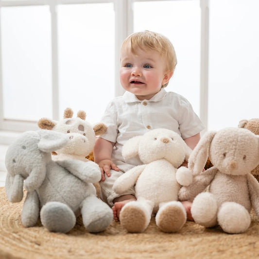 Eclectic Nattou grey elephant plush toy sitting on a rug next to a baby and other stuffed animal friends