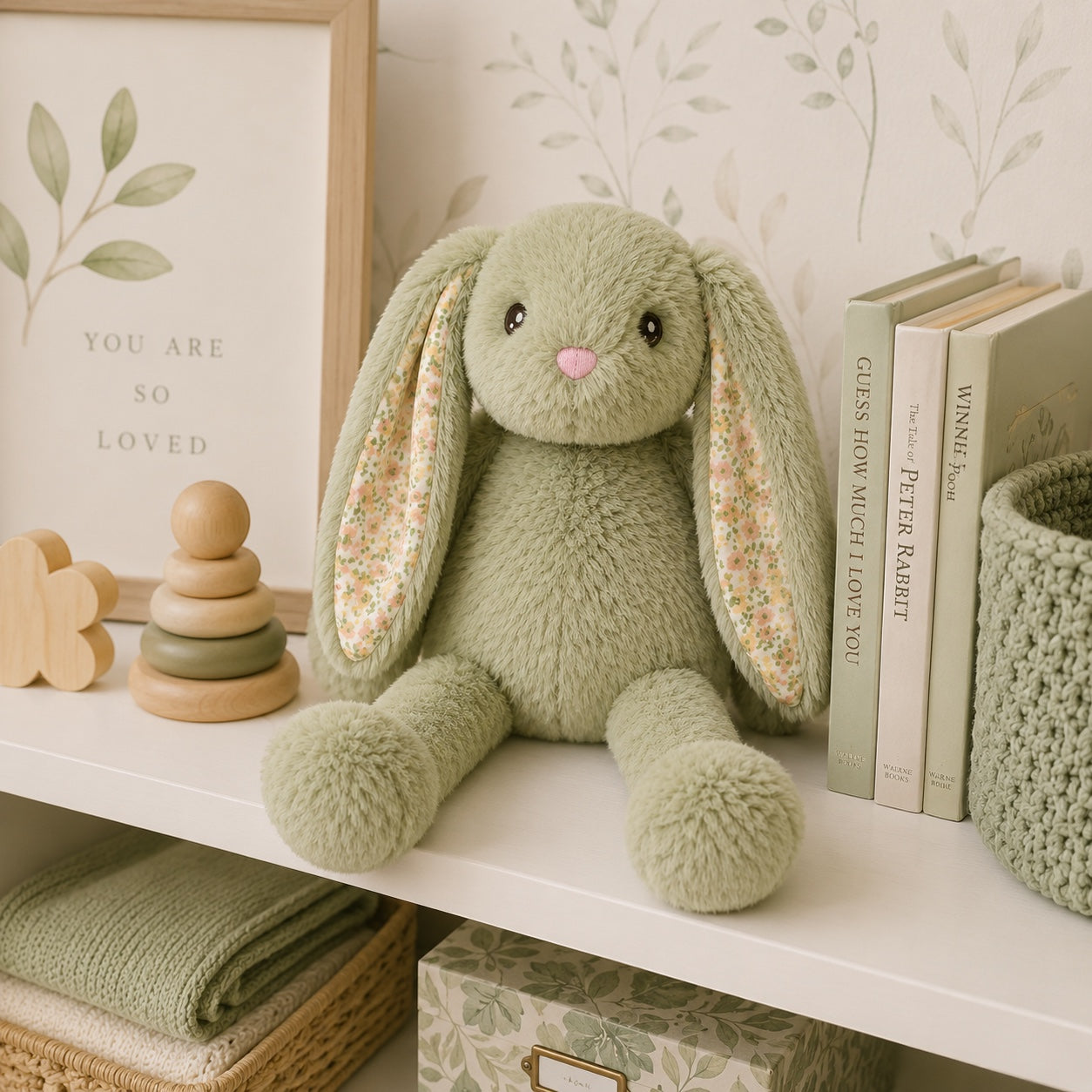 Eclectic Peluche sage green plush bunny with floral lined ears sitting on a nursery shelf with books and decor.