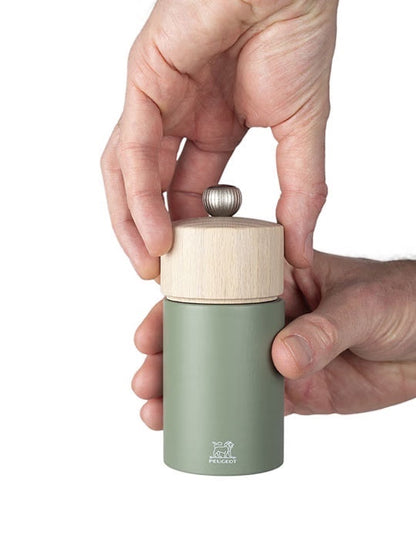 Eclectic Peugeot Boreal 12 cm pepper mill in fern green beechwood with a natural wood top held in hands
