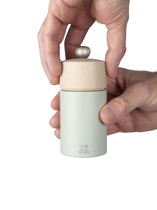 Eclectic Peugeot Boreal 12cm salt mill in sage green beechwood held by hands to adjust the top grind setting button