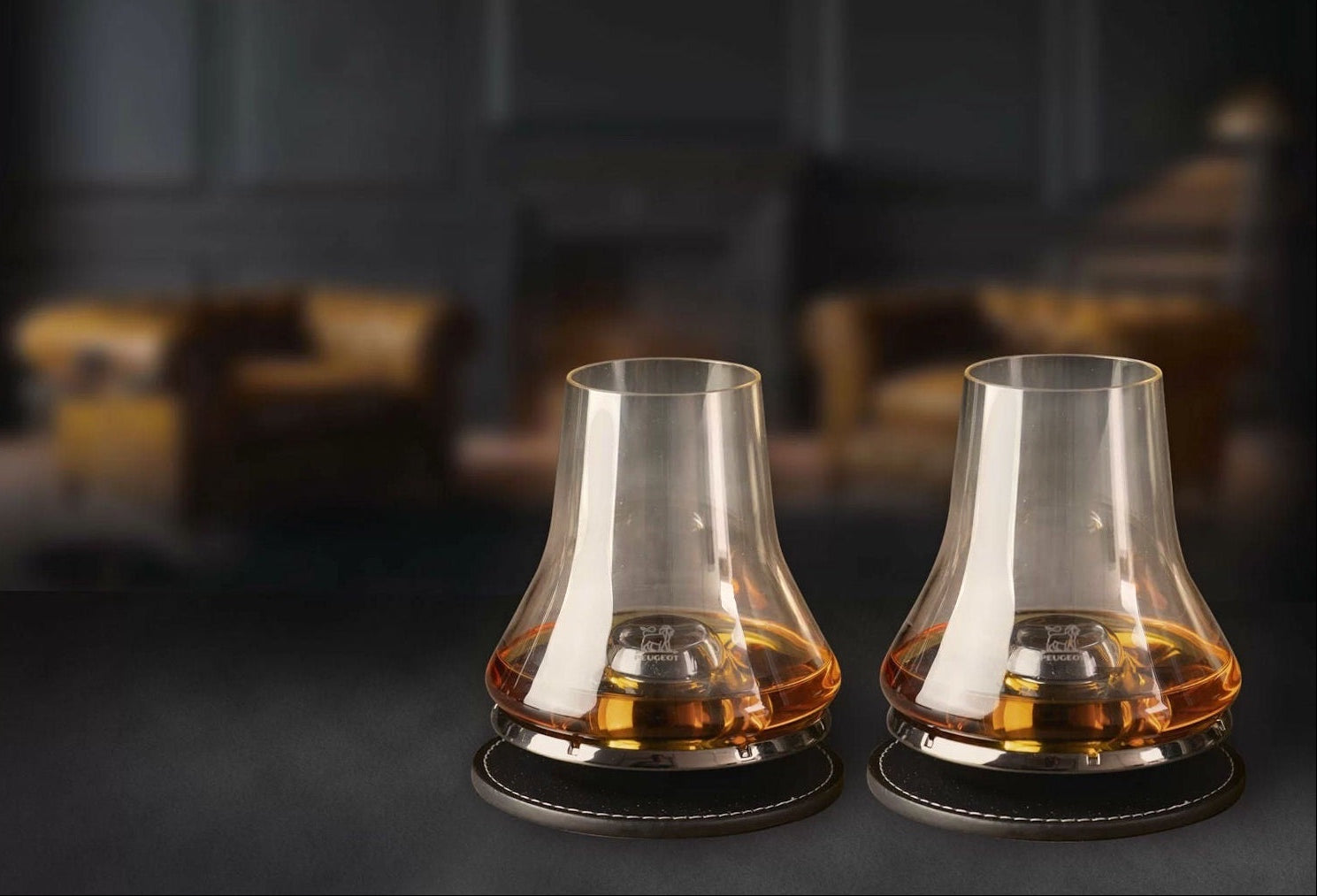 Eclectic Peugeot whisky tasting glass set with chilling bases and coasters on a dark surface.