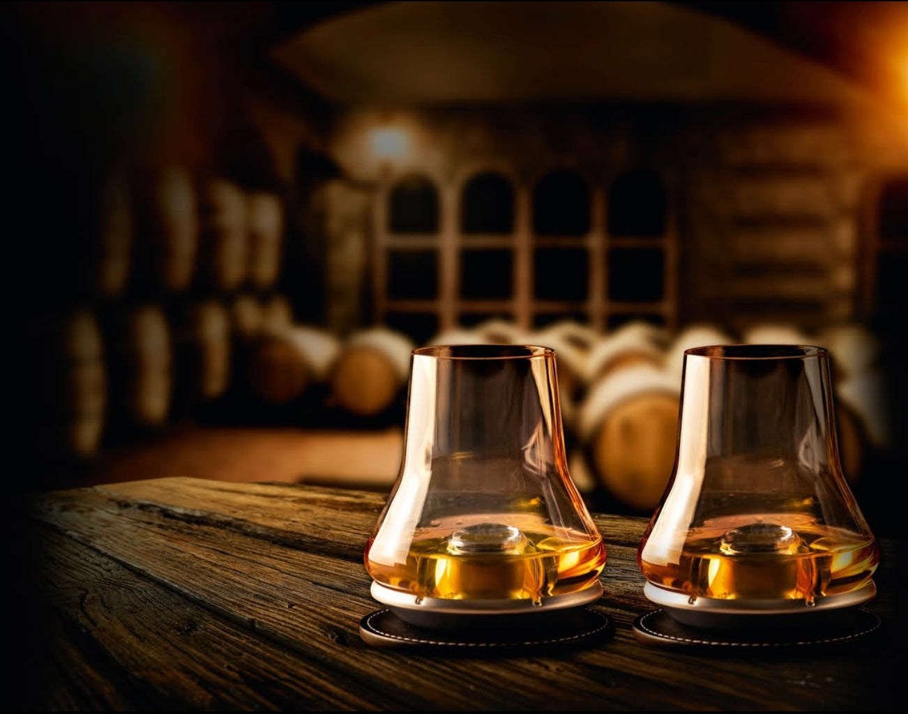 Eclectic Peugeot whisky tasting glass set with chilling bases and coasters on a wooden table in a cellar.