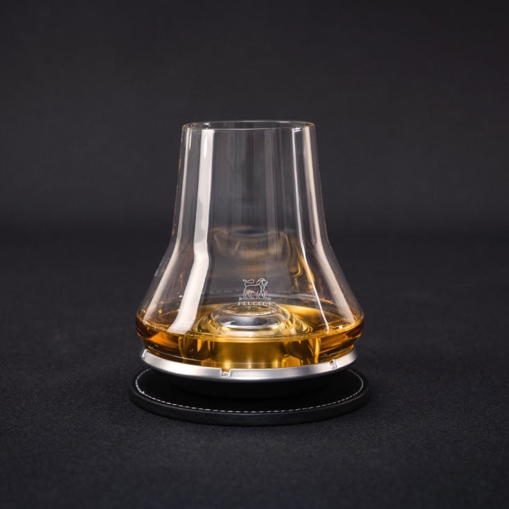 Eclectic Peugeot whisky tasting glass with a domed chilling base on a black coaster against a dark background