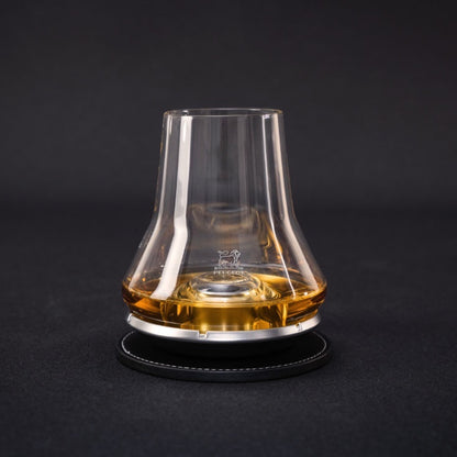Eclectic Peugeot whisky tasting glass with a domed chilling base on a black coaster against a dark background