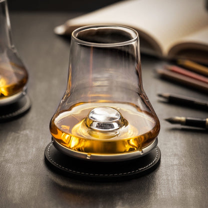 Eclectic Peugeot whisky tasting glass with a domed chilling base on a black coaster, filled with golden amber spirit.