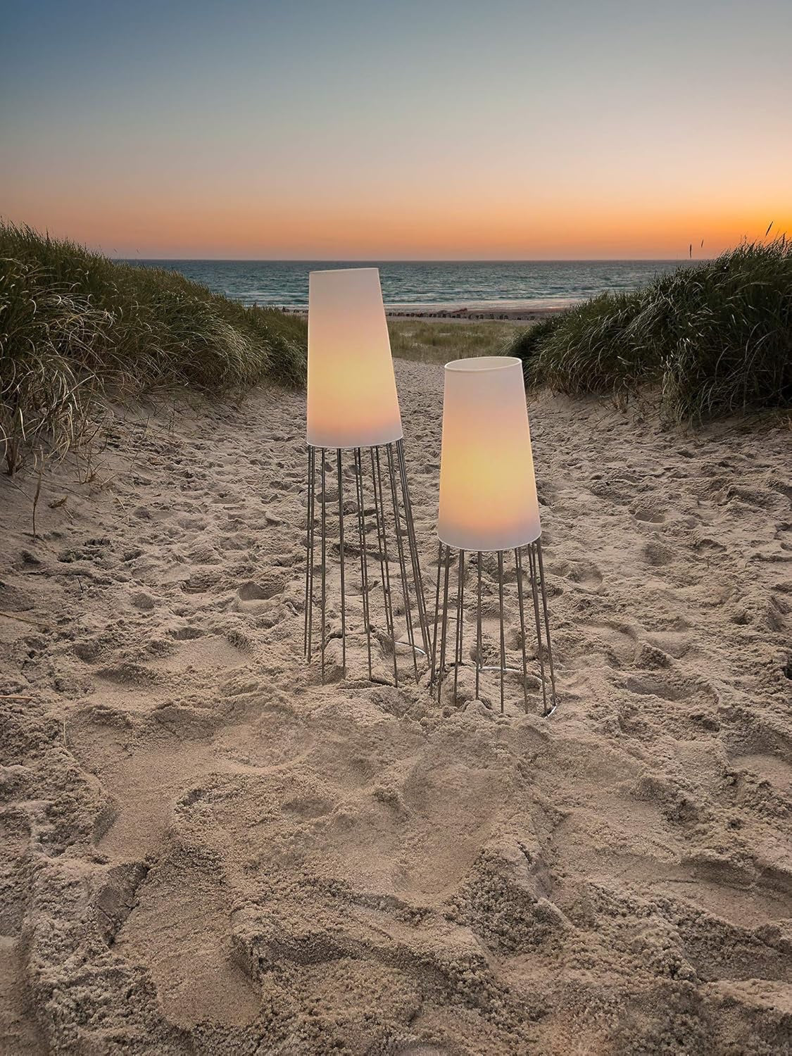 Eclectic Philippi Lighthouse tea light holders with frosted glass and silver bases glowing on a sandy beach at sunset