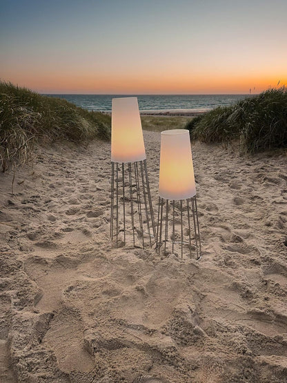 Eclectic Philippi Lighthouse tea light holders with frosted glass and silver bases glowing on a sandy beach at sunset