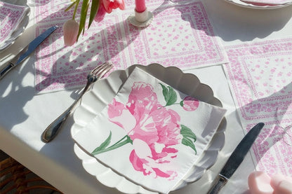 Eclectic Pivoine airlaid dinner napkin with a pink peony motif on a white scalloped plate at a French table setting.