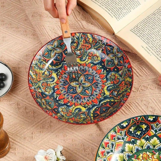 Eclectic red ceramic pasta bowl featuring a vibrant bohemian mandala pattern, shown with a fork on a textured cloth.