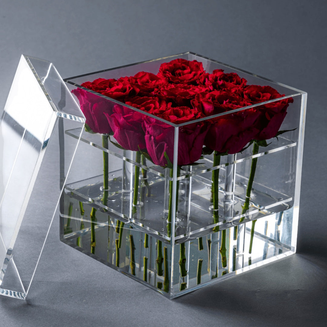 Eclectic rose box featuring deep red roses arranged in a clear acrylic square container with a removable lid.