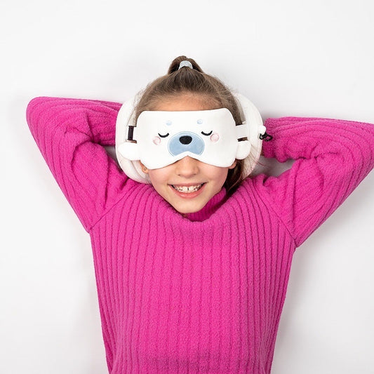 Eclectic Relaxeazzz Kai the Seal travel pillow and matching eye mask worn by a girl in a bright pink sweater