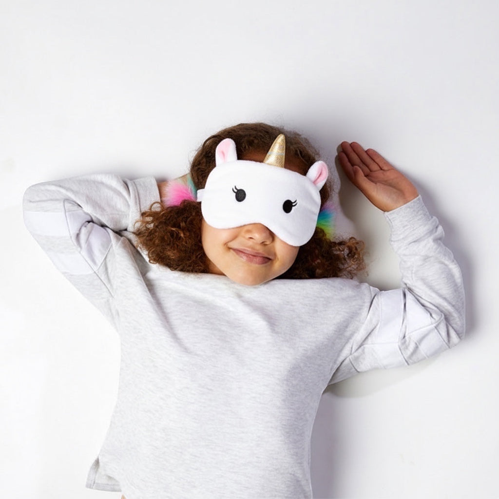 Eclectic Relaxeazzz Astrid the Unicorn eye mask worn by a young girl with curly hair against a white background