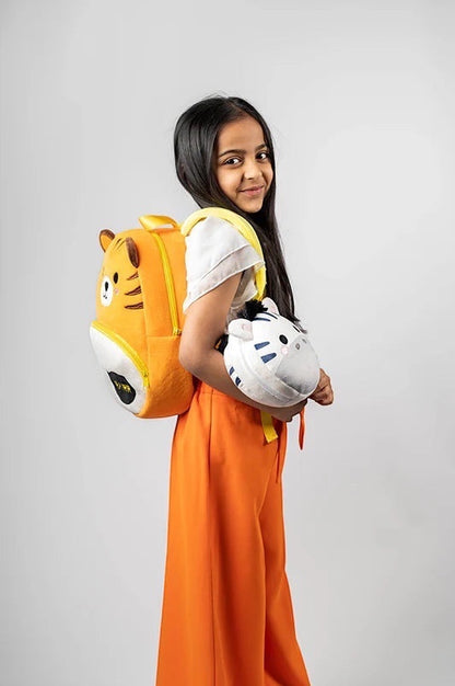 Eclectic Relaxeazzz Bali the Zebra plush travel pillow held by a young girl wearing an orange outfit and tiger bag