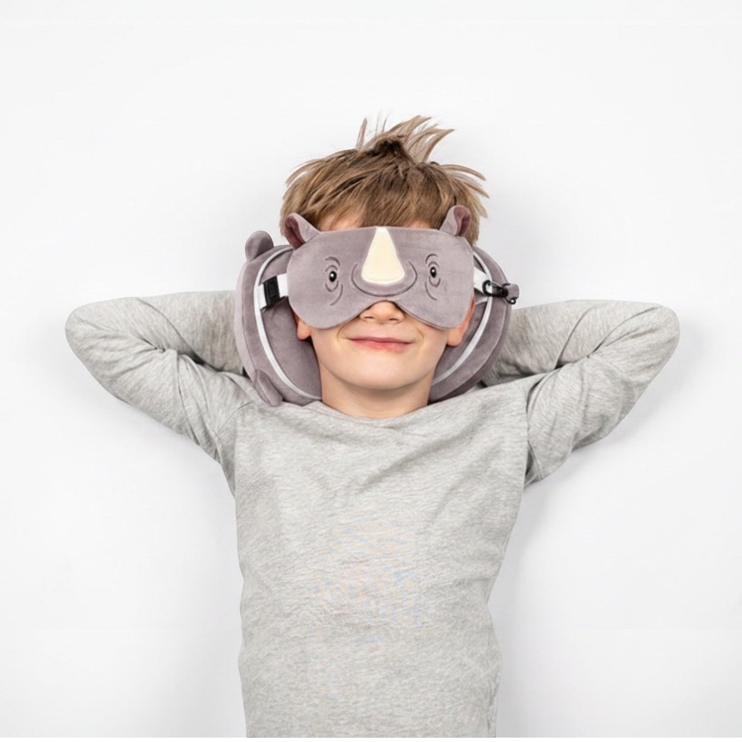 Eclectic child wearing a grey Remy the Rhino travel pillow and matching eye mask for comfortable travel rest
